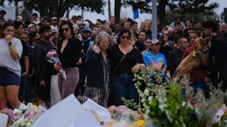 People stand next to a memorial for the victims of the shooting at Bondi Beach
