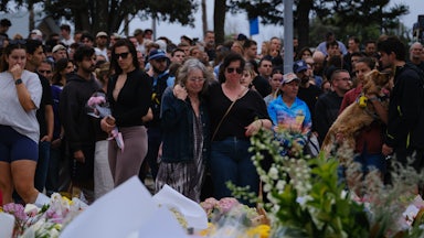 People stand next to a memorial for the victims of the shooting at Bondi Beach