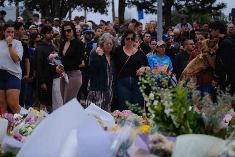 People stand next to a memorial for the victims of the shooting at Bondi Beach