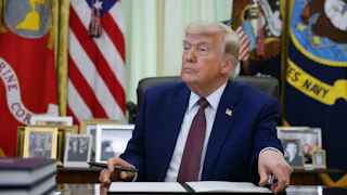 President Trump signs an executive order in the Oval Office.