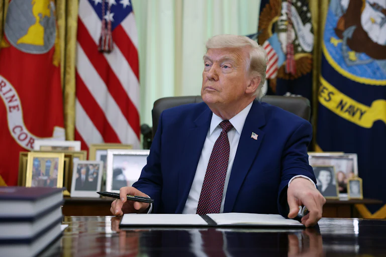 President Trump signs an executive order in the Oval Office.