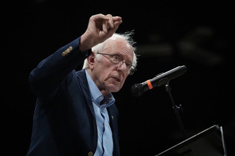 Bernie Sanders speaks into a mic while making a hand gesture.