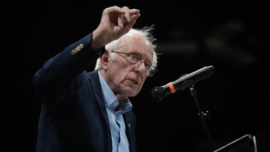 Bernie Sanders speaks into a mic while making a hand gesture.