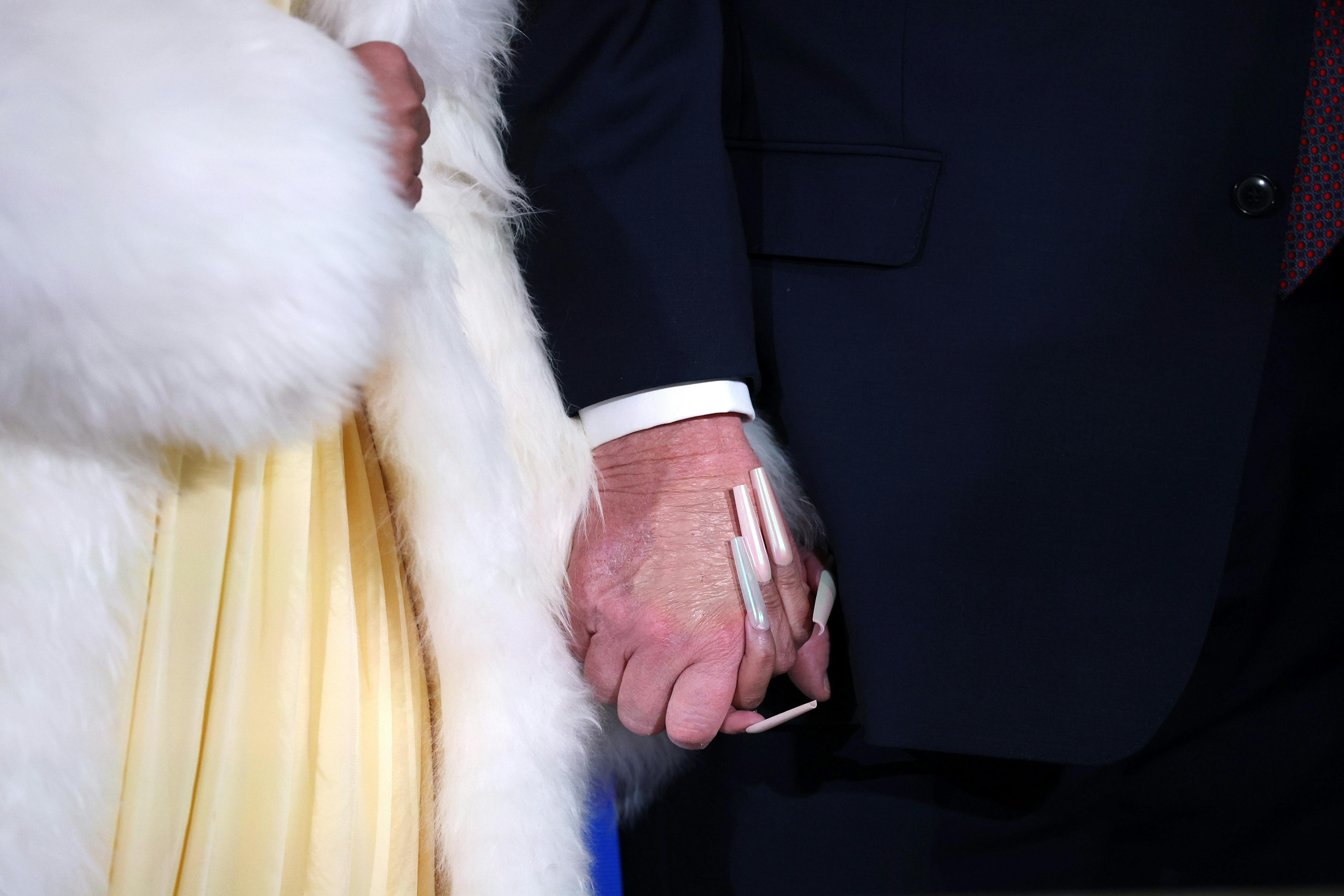 Close-up of Nicki Minaj and Donald Trump holding hands, with Nicki’s long nails and the concealer on Trump’s hand