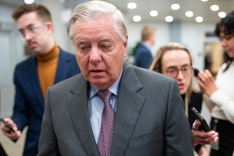 Lindsey Graham looks down while walking in the Capitol
