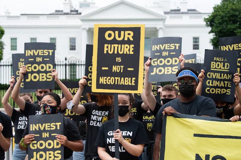 Climate activists hold signs in front of the White House.