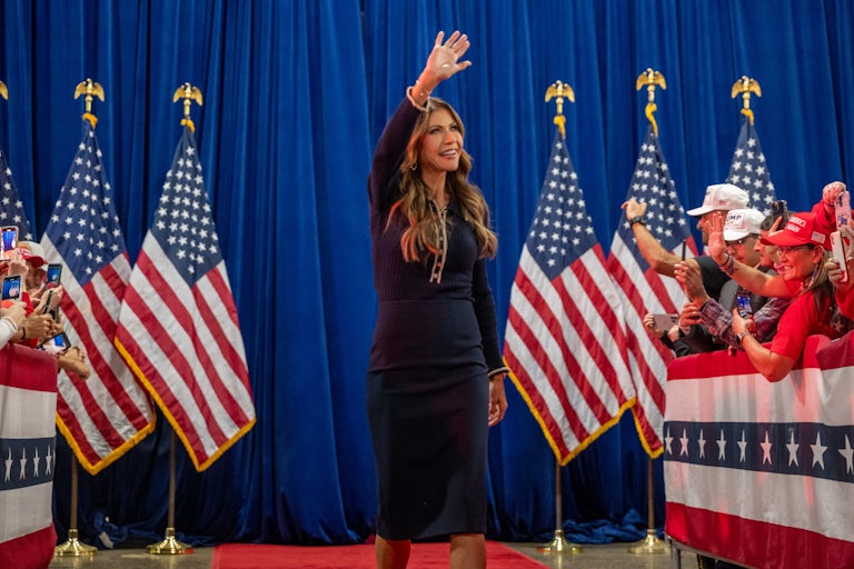 Kristi Noem waves while walking out during a Donald Trump event