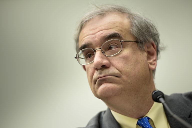 A man with glasses wearing a suit looks out as he listens to a question