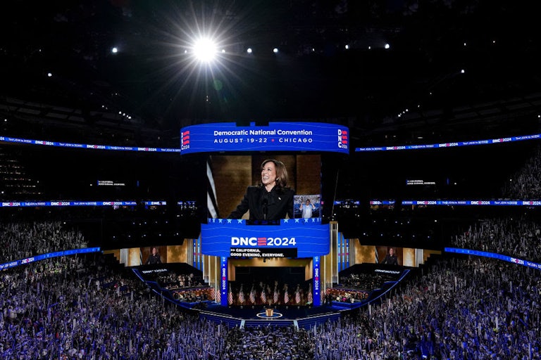 This zoomed-out shot shows the convention all with thousands of attendees, Kamala Harris on stage, and video of her projected above.