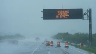 Cars drive under a road sign that says "Hurricane warning in effect" during Hurricane Milton
