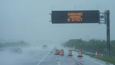 Cars drive under a road sign that says "Hurricane warning in effect" during Hurricane Milton