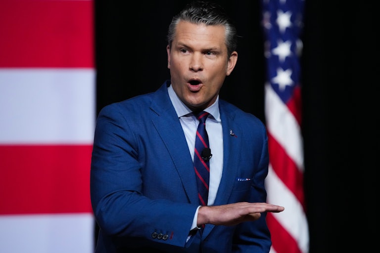 War Secretary Pete Hegseth holds his hand horizontally in front of his torso while speaking to military leaders at Quantico
