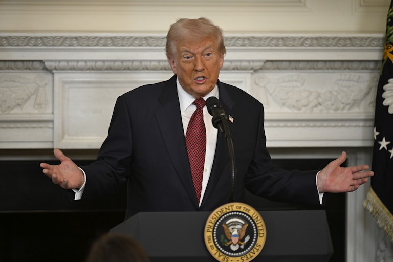 Donald Trump holds his arms out to the side while speaking at a podium