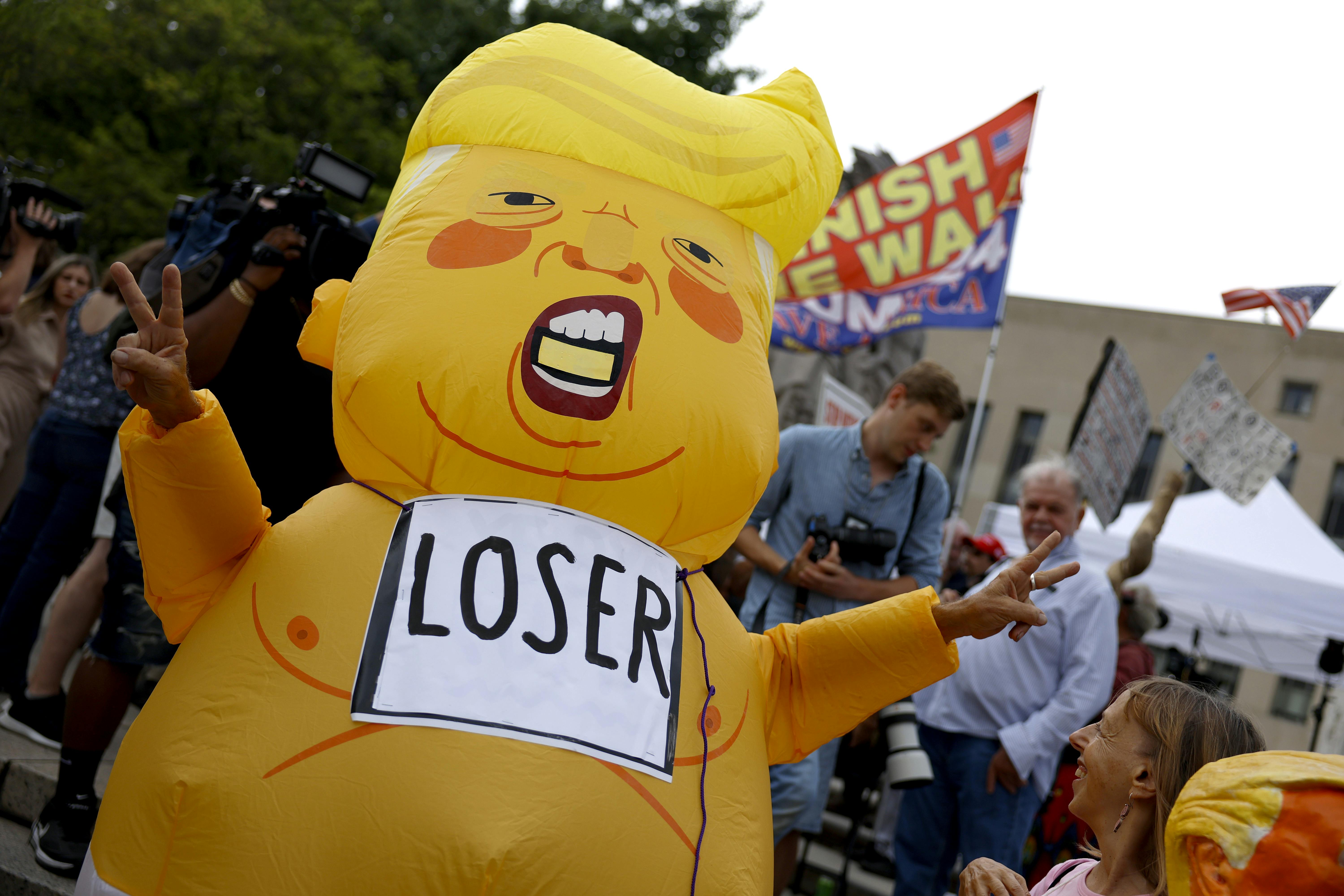 A protester in an inflatable Trump "loser" suit