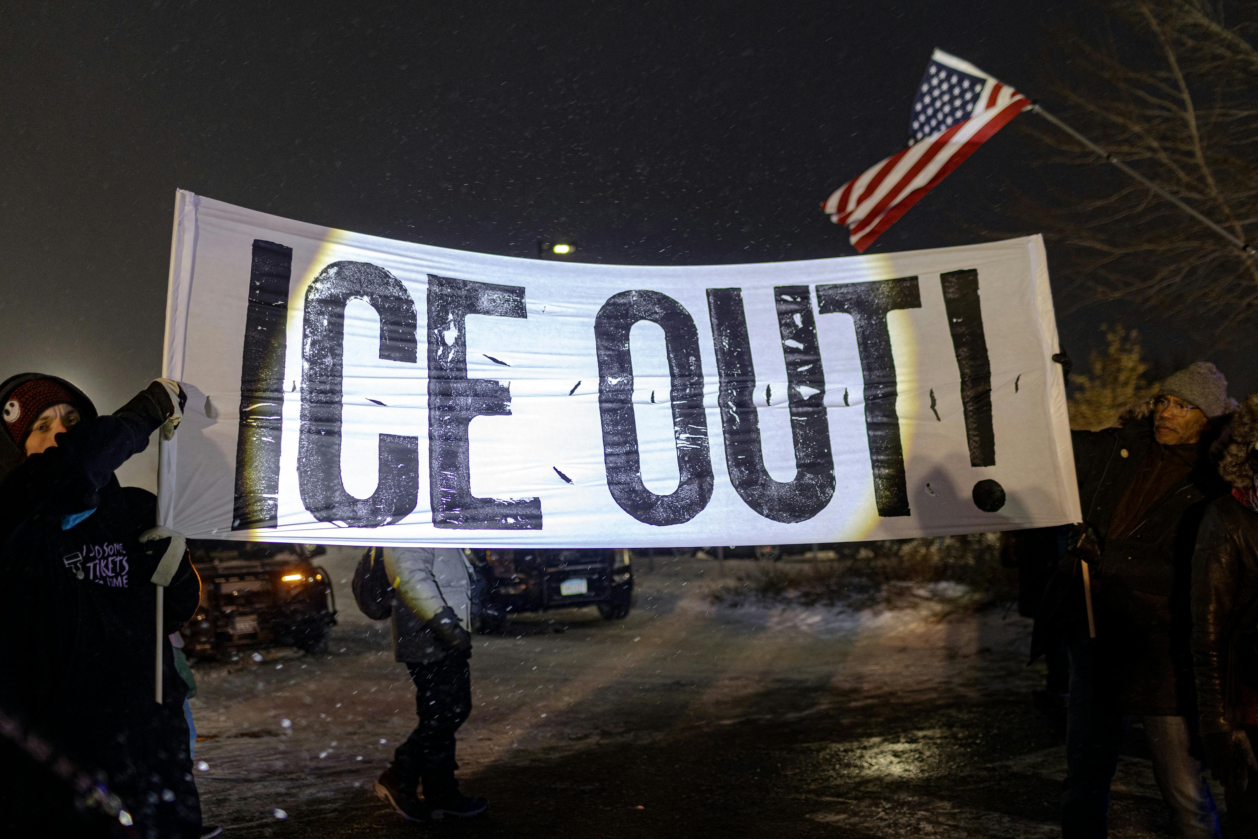 People hold up a banner that says, "ICE Out" during a protest in Minneapolis, Minnesota