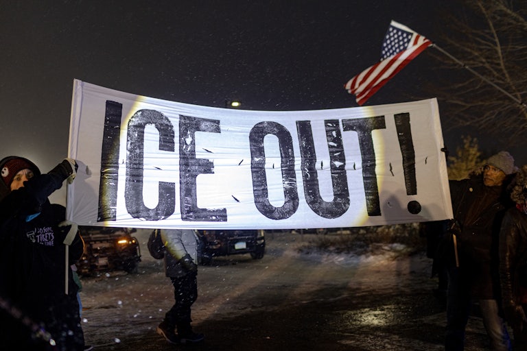 People hold up a banner that says "ICE Out!" during a protest in Minneapolis.
