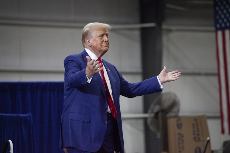 Donald Trump raises his hands outward (as if in welcome) at a campaign rally