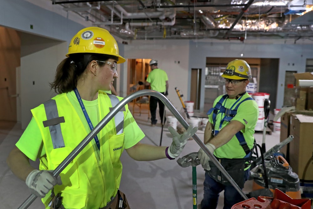 Alicia Miksic. apprentice electrician, bends an electrical pipe with electrician Adam DeFilippo at a work site in Boston.