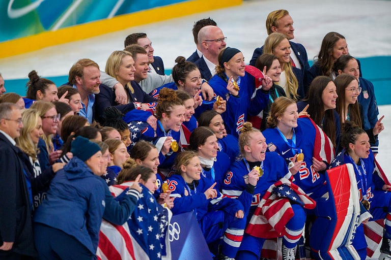 The U.S. women's hockey team celebrates their win at the Olympics, holding up their gold medals.