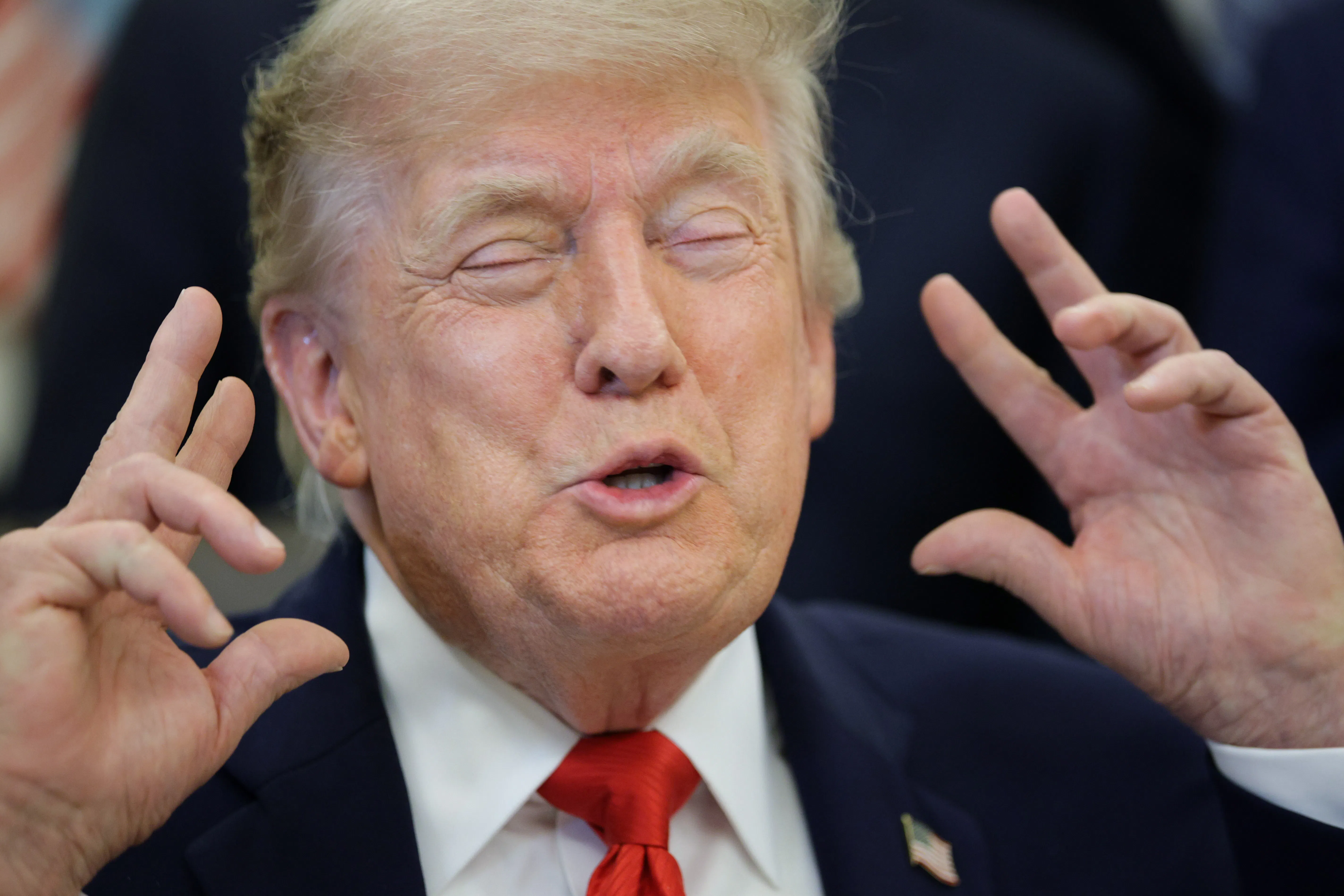 Donald Trump raises hands in gesture with eyes closed