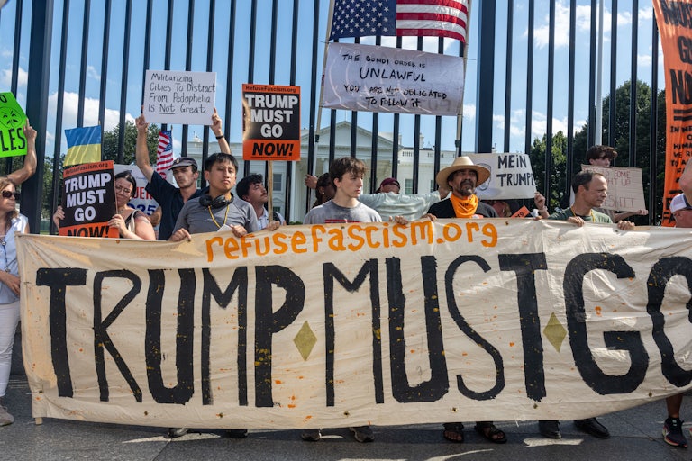 Protesters in Washington, D.C. stand in front of a sign denouncing Trump's crackdown.