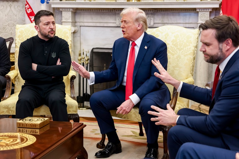 Donald Trump and JD Vance hold up a hand to Ukrainian President Volodymyr Zelensky, who crosses his arms, as the three of them speak in the White House's Oval Office.