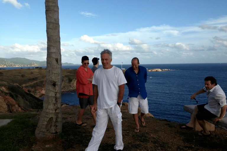 Howard Lutnick and Jeffrey Epstein smile in a group with three other men on Epstein's island, by the water.