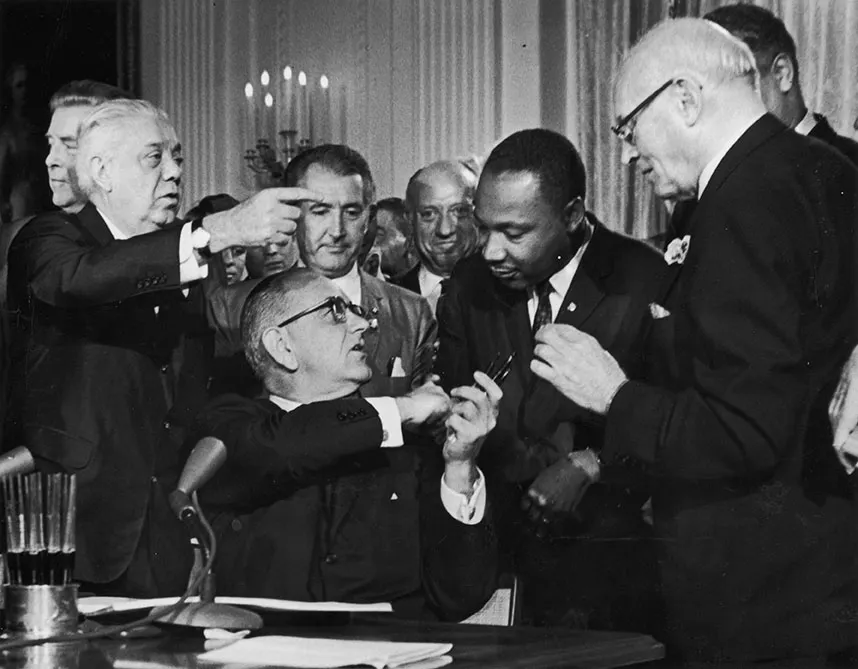 Black and white photograph of President Lyndon B. Johnson handing a signing pen to Martin Luther King Jr. at the Civil Rights Act signing, July 2, 1964 