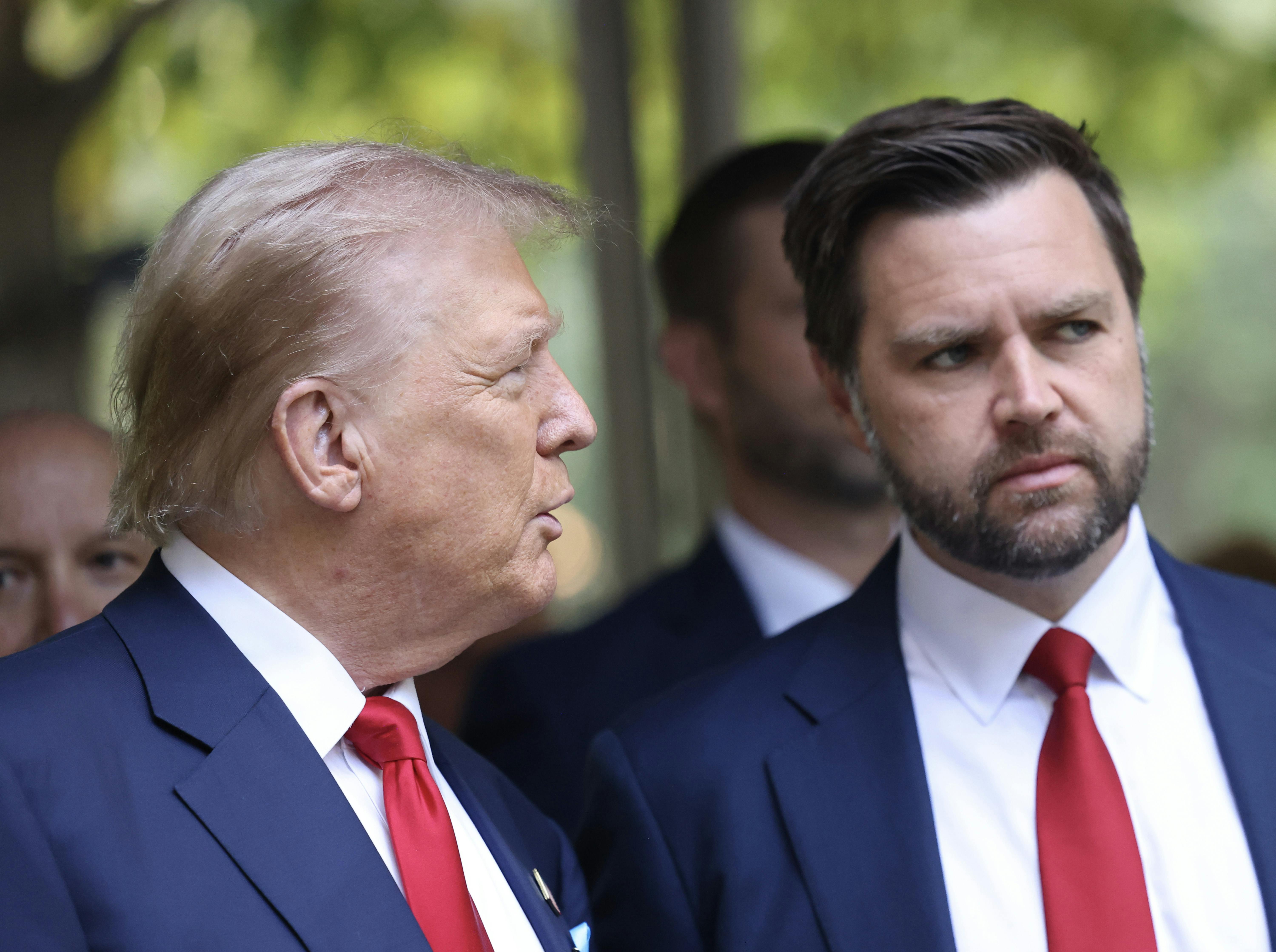 Trump turns toward Vance, with people behind them.