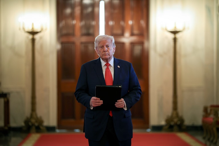 Donald Trump holds a binder and walks in the White House