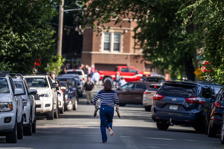A parent runs toward the school during an active shooter situation at the Annunciation Church in Minneapolis, Minnesota. She runs barefoot, holding her shoes in her hands.