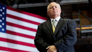 Rush Limbaugh, seen from below, standing in front of an American flag.