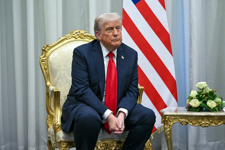 Donald Trump sits with his hands folded between his knees