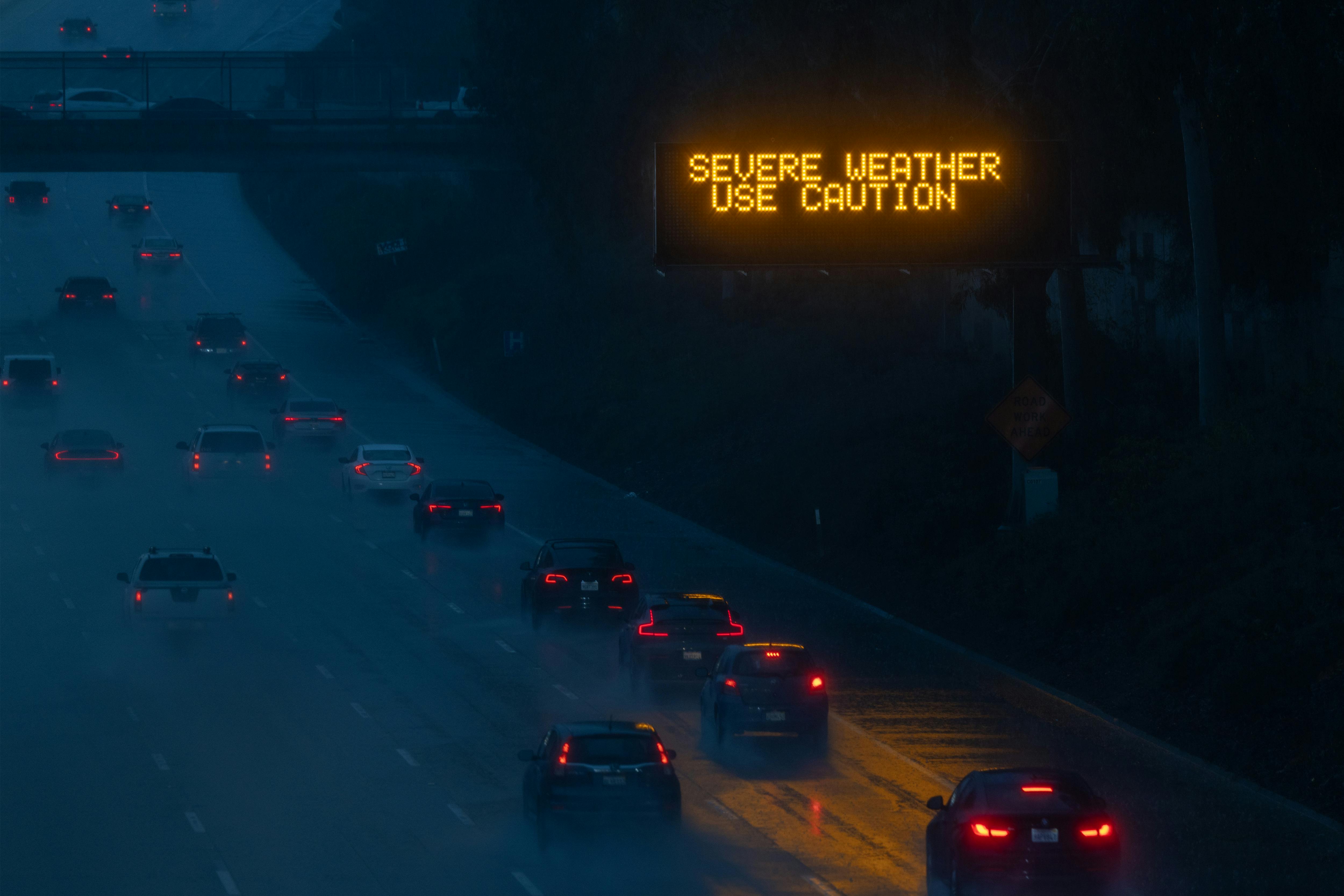 An illuminated sign along a dark and rainy freeway says "Severe Weather. Use Caution."