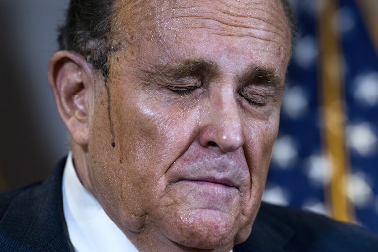 Rudy Giuliani, hair dye dripping off his head, closes his eyes as if in pain or defeat