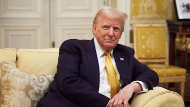 Donald Trump smiles while sitting on a couch