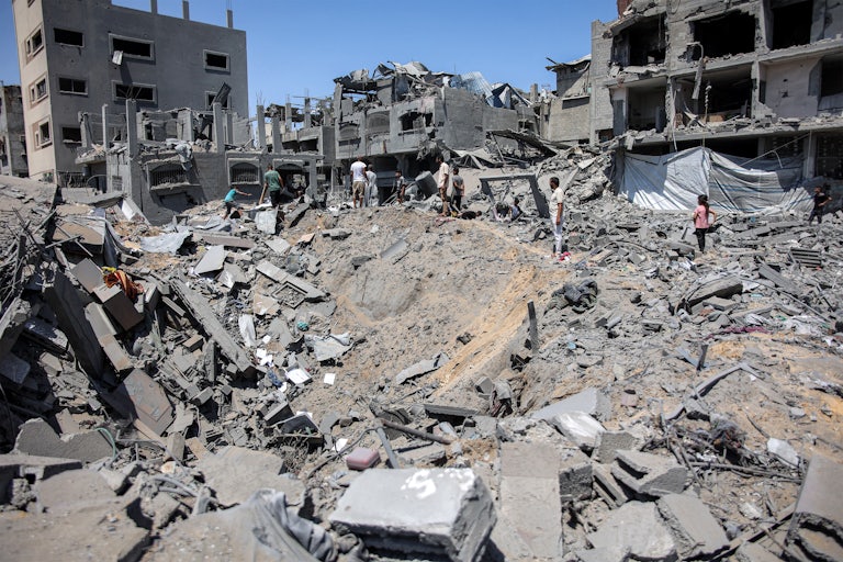 People stand around a crater made by Israeli bombardment in Gaza City
