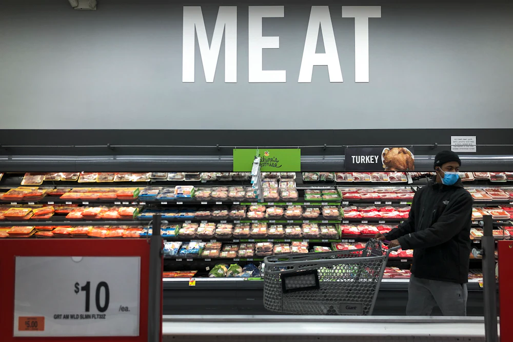 A man shops in the meat section at a grocery store.