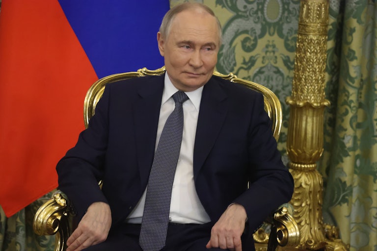 Russian President Vladimir Putin grimaces while sitting in a gold chair