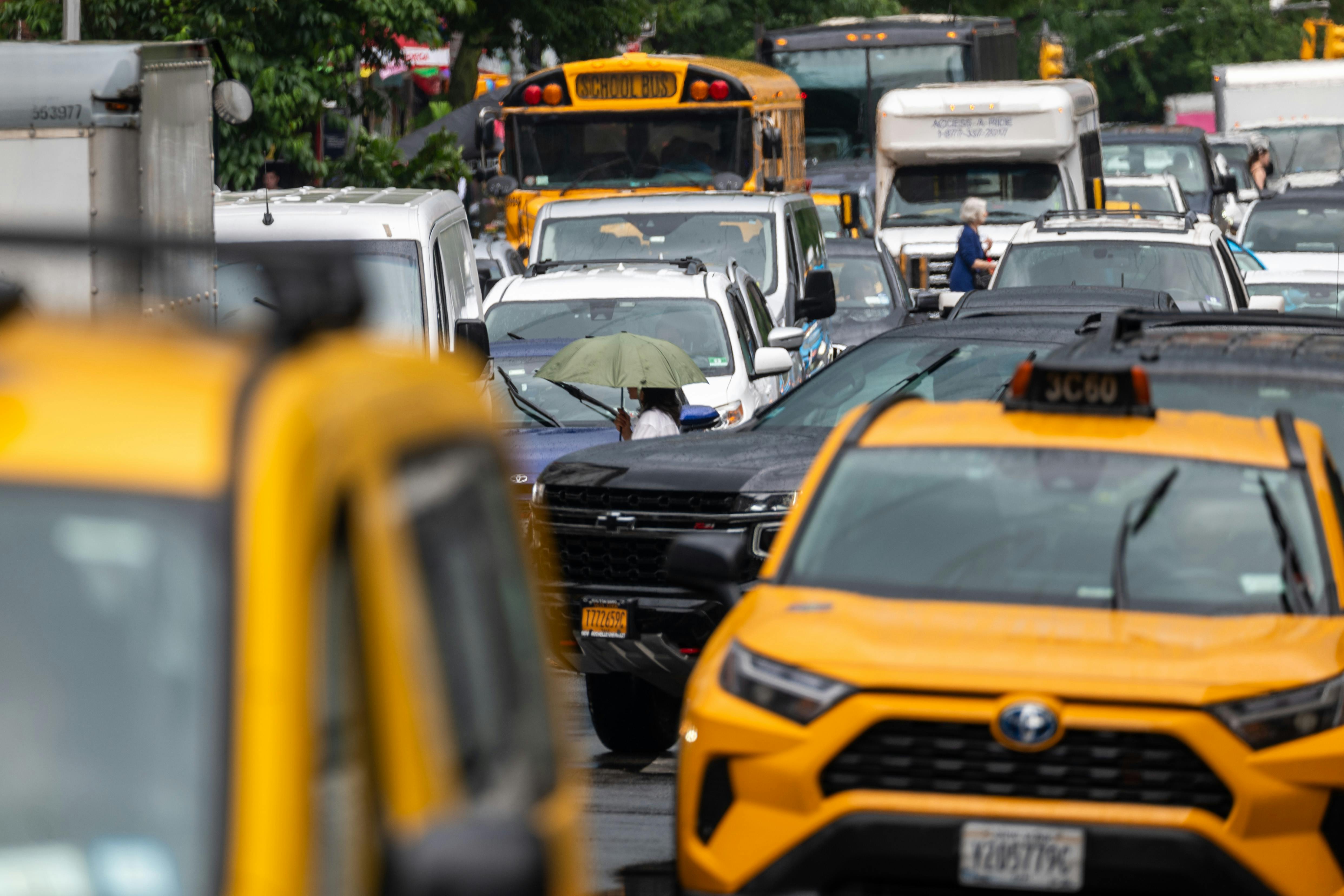 Cabs, a school bus, and many passenger vehicles sit in bumper-to-bumper traffic.