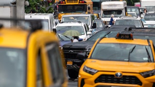 Cabs, a school bus, and many passenger vehicles sit in bumper-to-bumper traffic.