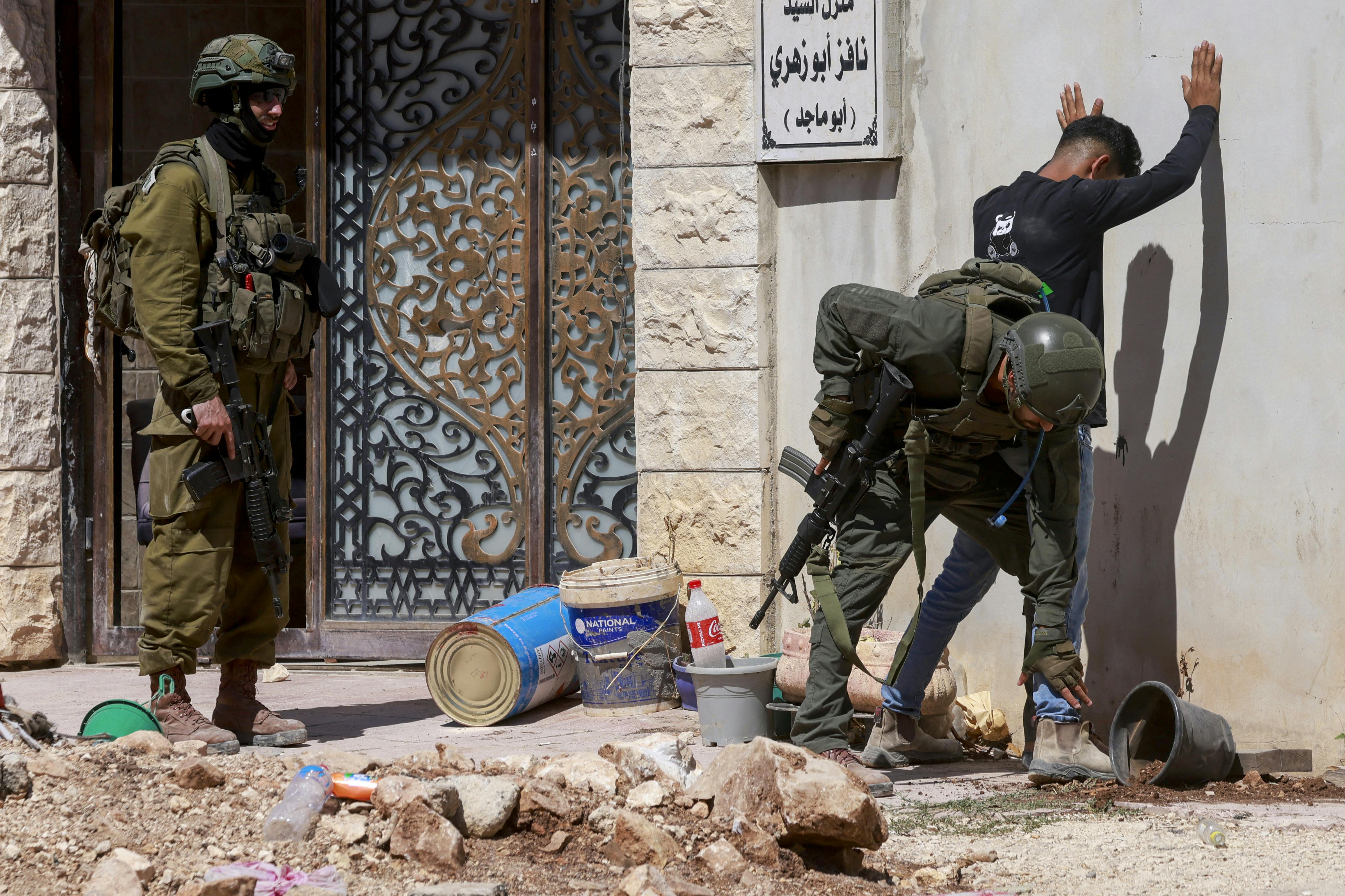 Israeli soldiers check a Palestinian man at the entrance of Tulkarem camp, in the occupied West Bank, during a military operation on July 6, 2025. 