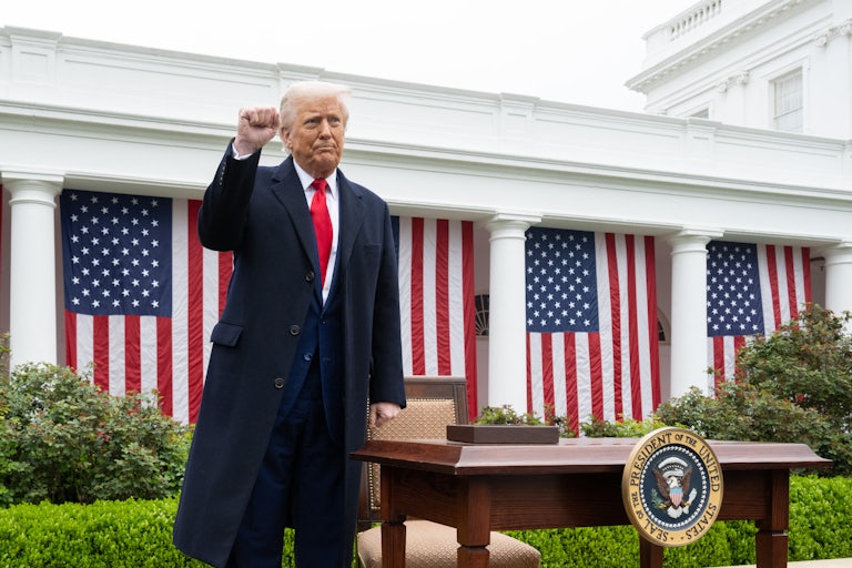 Donald Trump raises his fist while standing next to a desk in the White House Rose Garden
