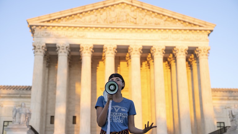 An activist speaks into a megaphone outside the Supreme Court in protest against the new Texas abortion law. 