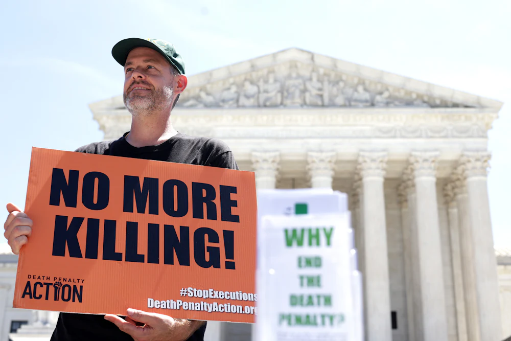 Scott Langley of Ghent, New York, hold sign that reads “No More Killing!” as he participates in a vigil against the death penalty in front of the U.S. Supreme Court.