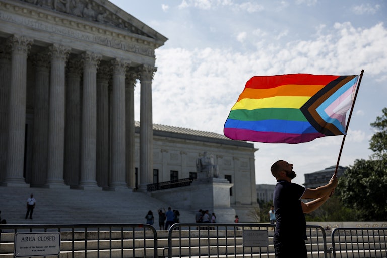 A person waves a pride flag in front of the U.S. Supreme Court