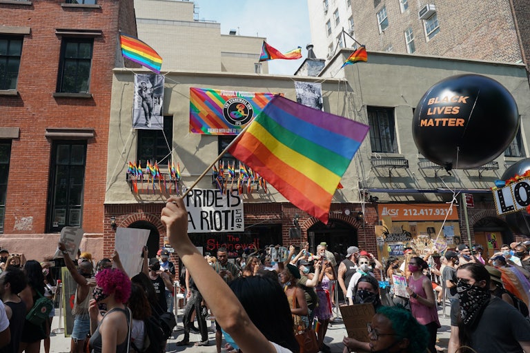 Protesters carrying signs walk past the Stonewall Inn. 