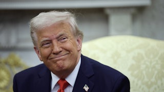 Donald Trump smiles while sitting in the Oval Office