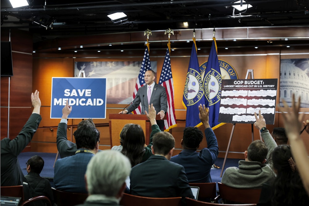 Hakeem Jeffries stands on a dais next to a large sign reading "Save Medicaid" and another reading "GOP Budget: Largest Medicaid Cut in U.S. History," with members of the press in front of him.