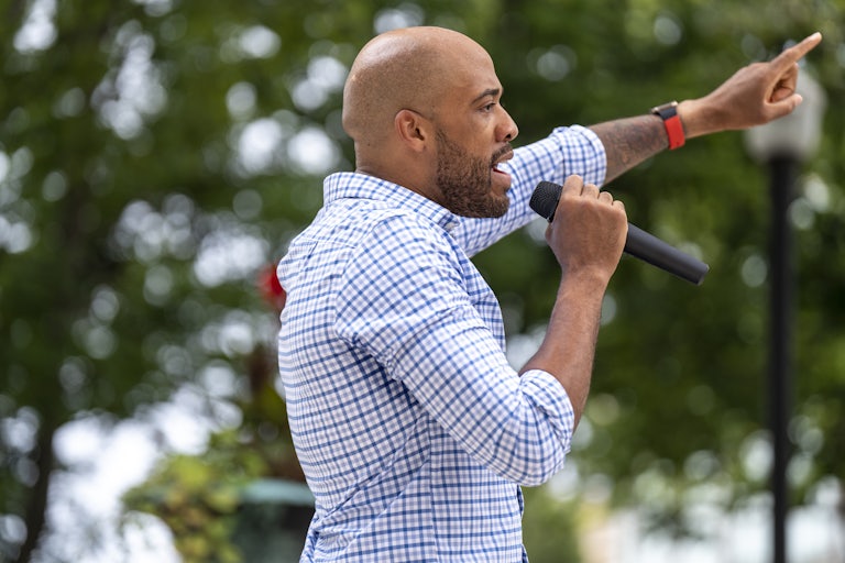Mandela Barnes speaks into a hand-held microphone while pointing with his other hand.